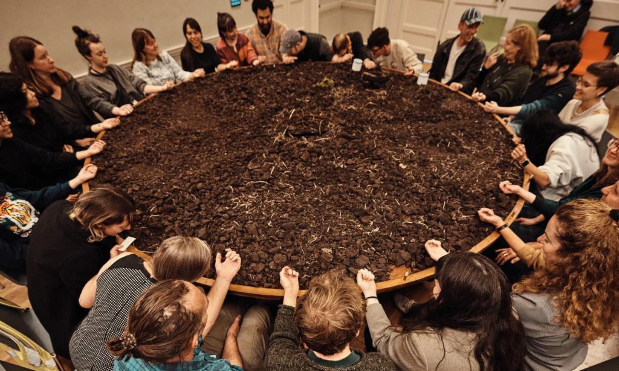 Group of people sitting around a table with peat on it for theatre performance