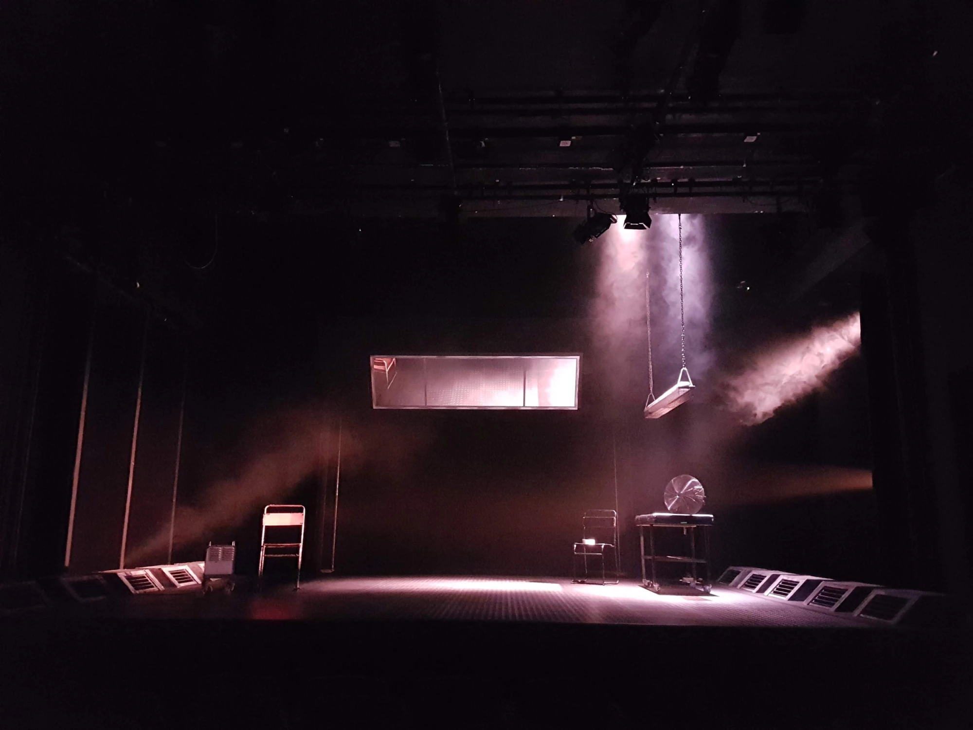 Dark set with spotlights lighting up swing, table and window.