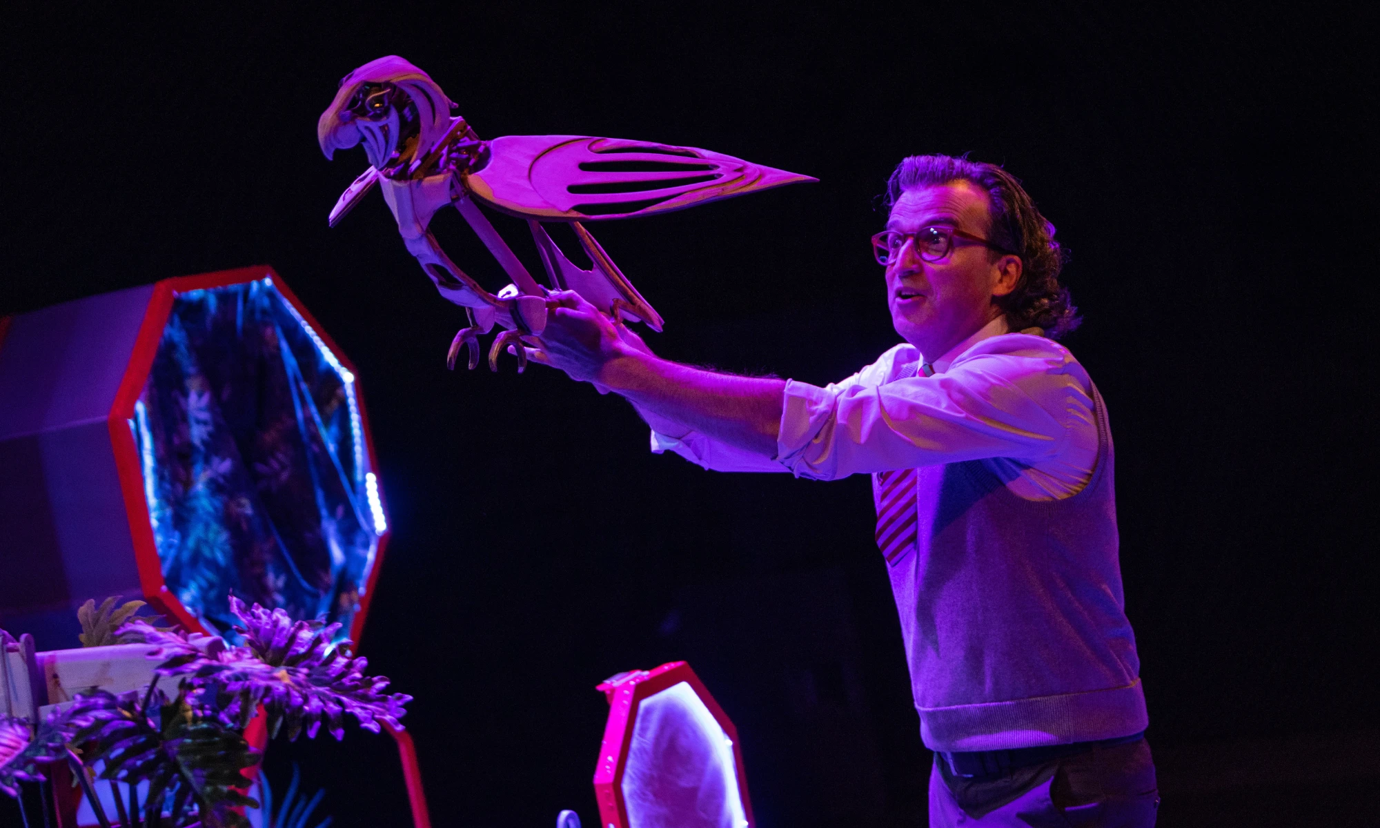 Photo of actor on stage with wooden parrot.