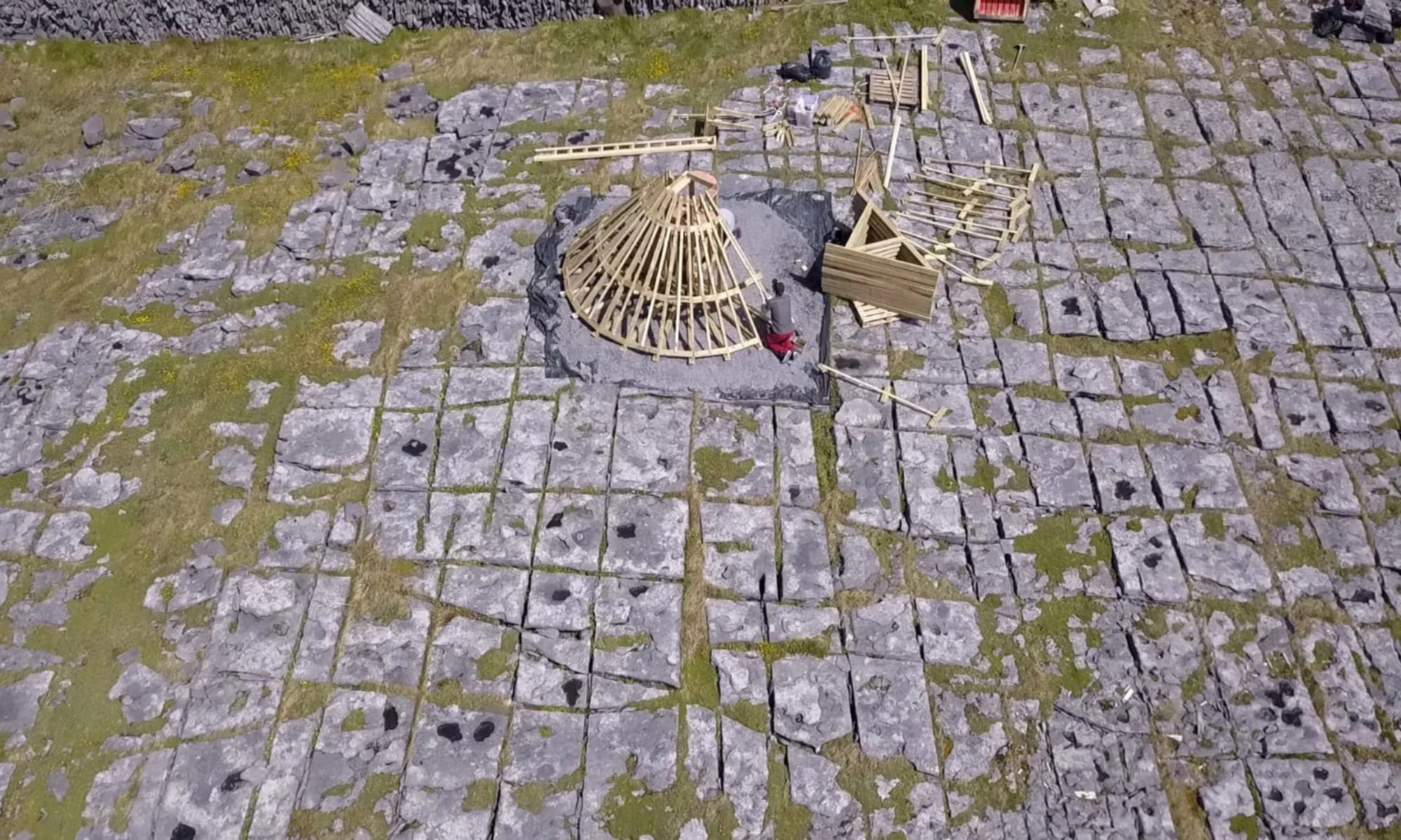 Conical wooden shape being constructed in rocky landscape.