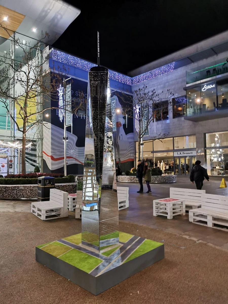 Miniature One World Trade Center building with shopping centre in background. 