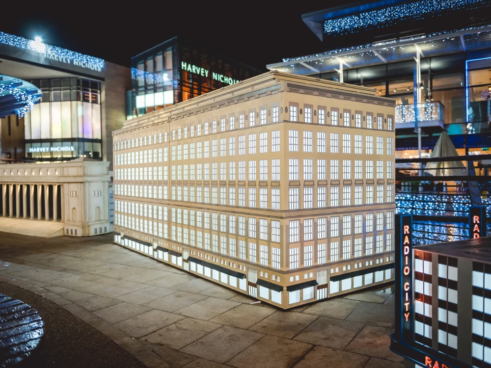 Miniature models of three New York buildings with shopping centre in background.
