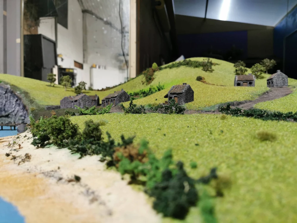 Miniature model of a landscape with fields, houses, beach and water.