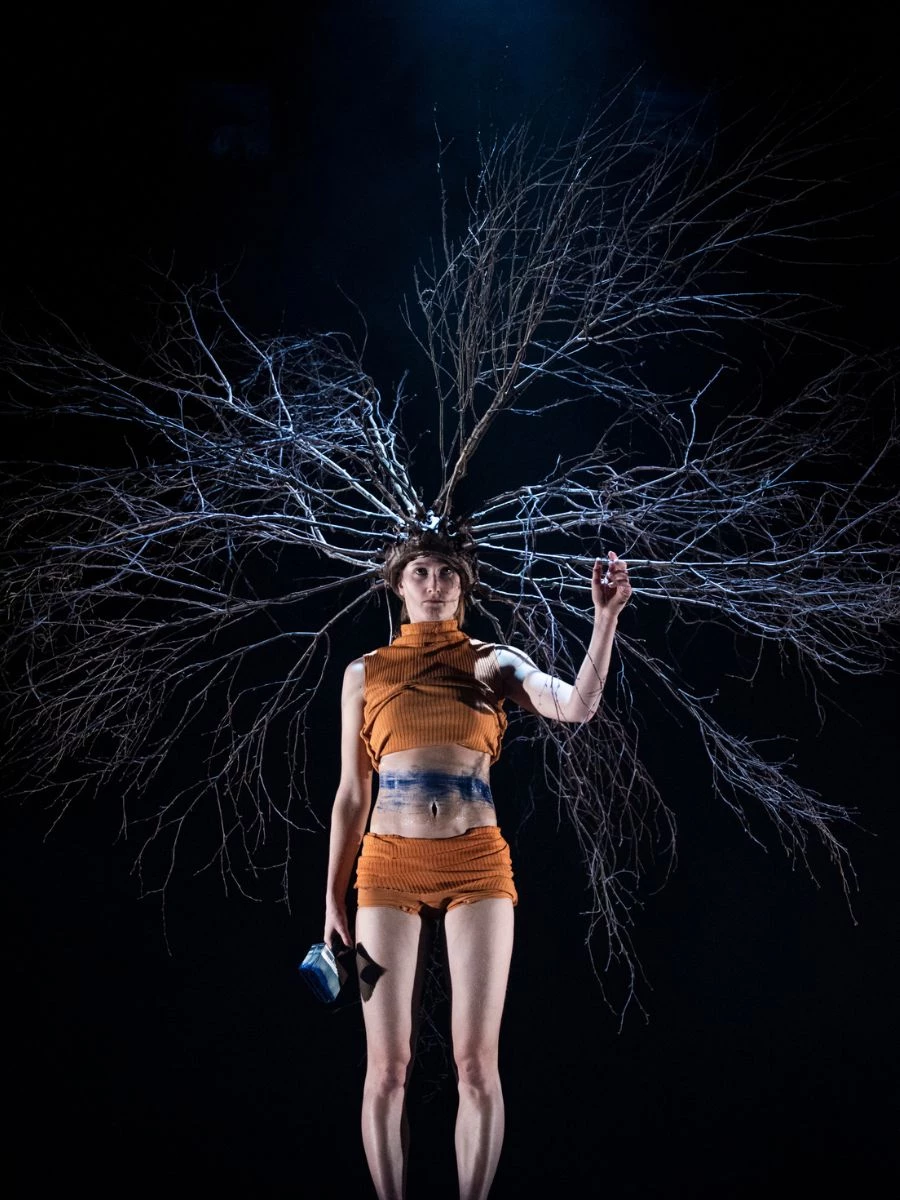 Woman with large headpiece standing on platform. 